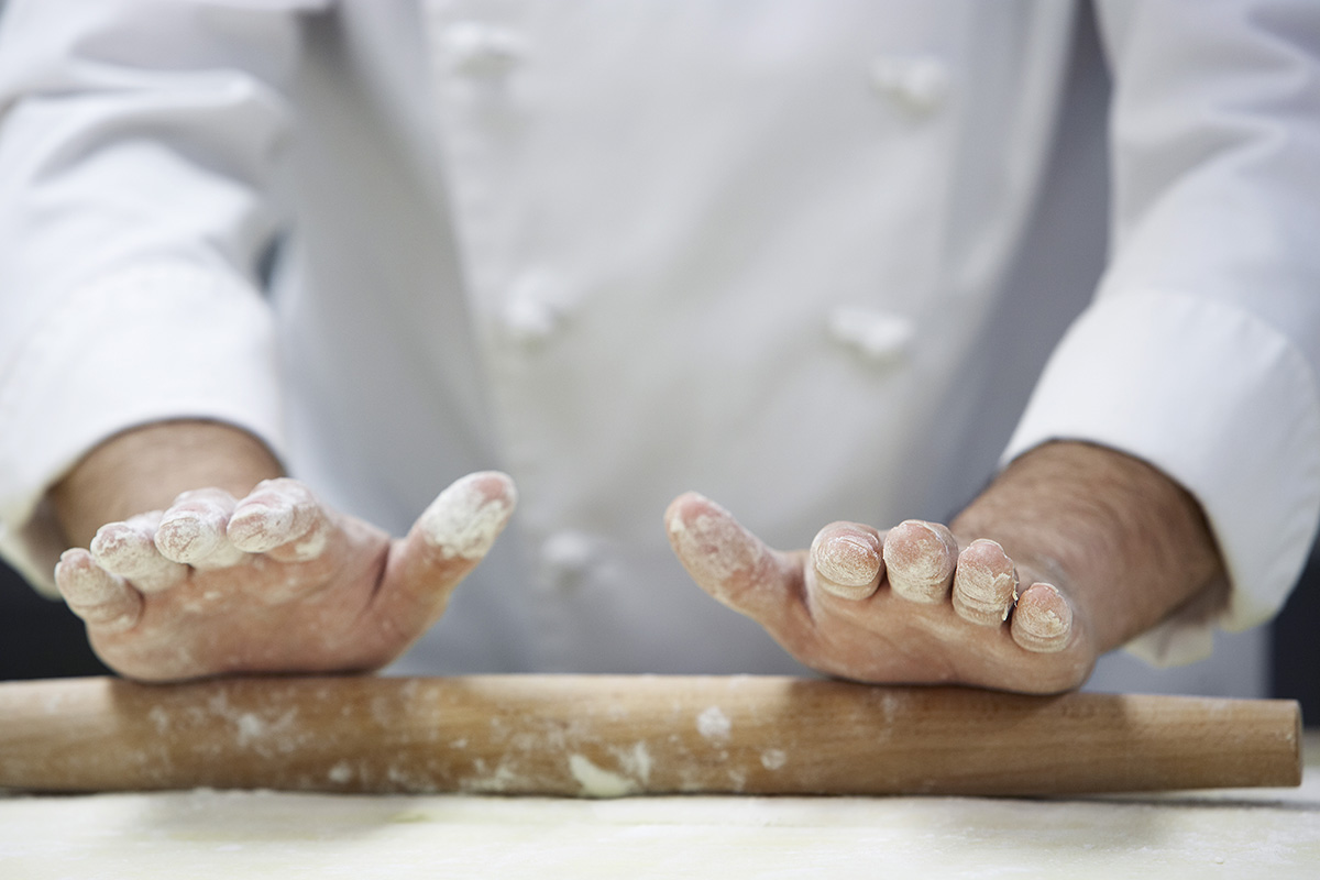 Chef rolling dough using rollingpin, close-up